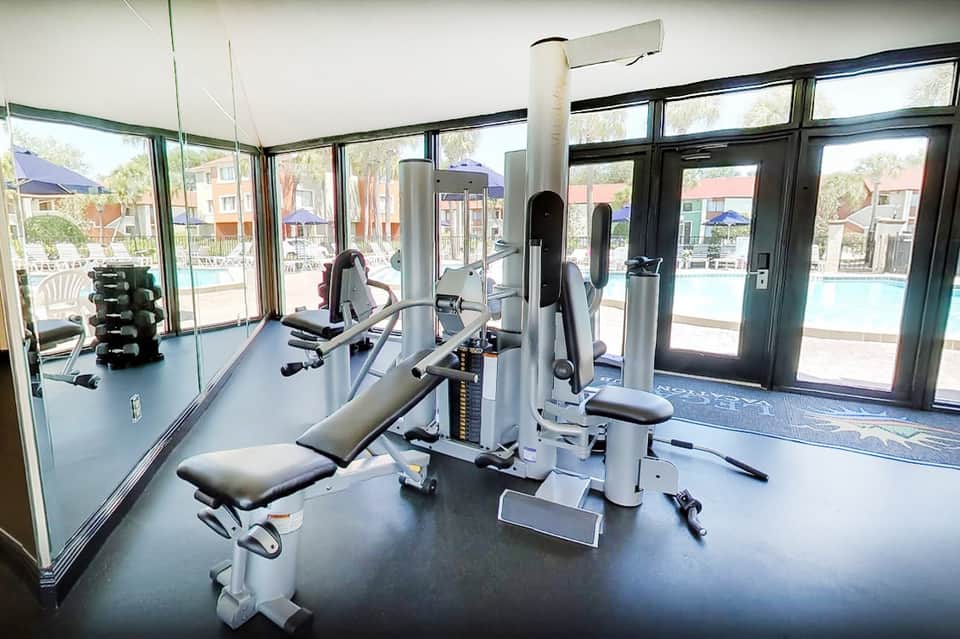 Fitness center with exercise equipment and large windows overlooking pool and resort grounds