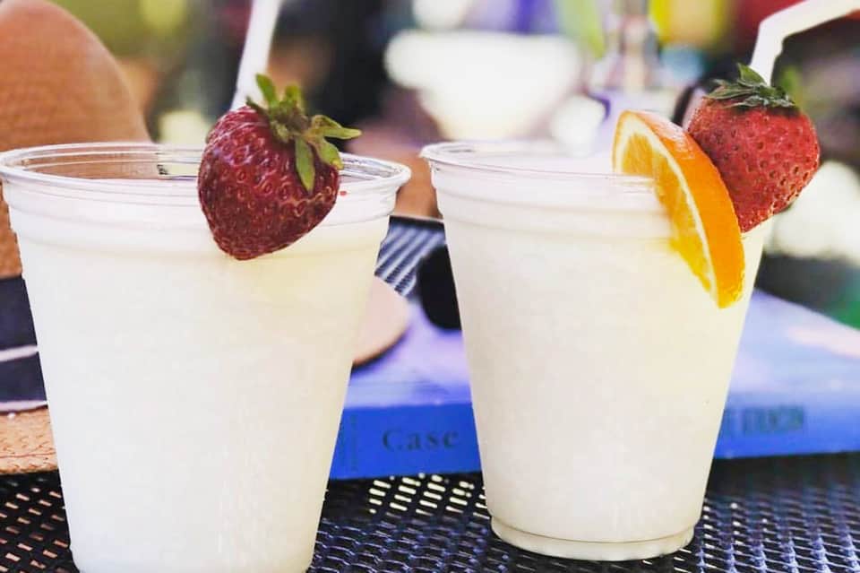 Two refreshing cocktails with strawberry and citrus garnishes on a bar counter