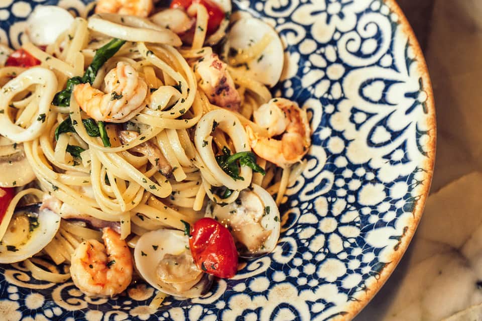Shrimp pasta with fresh herbs on decorative blue and white plate
