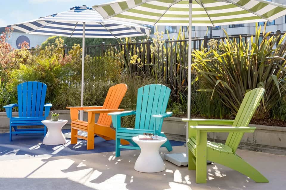Rooftop lounge area with colorful Adirondack chairs, umbrellas, and modern white building