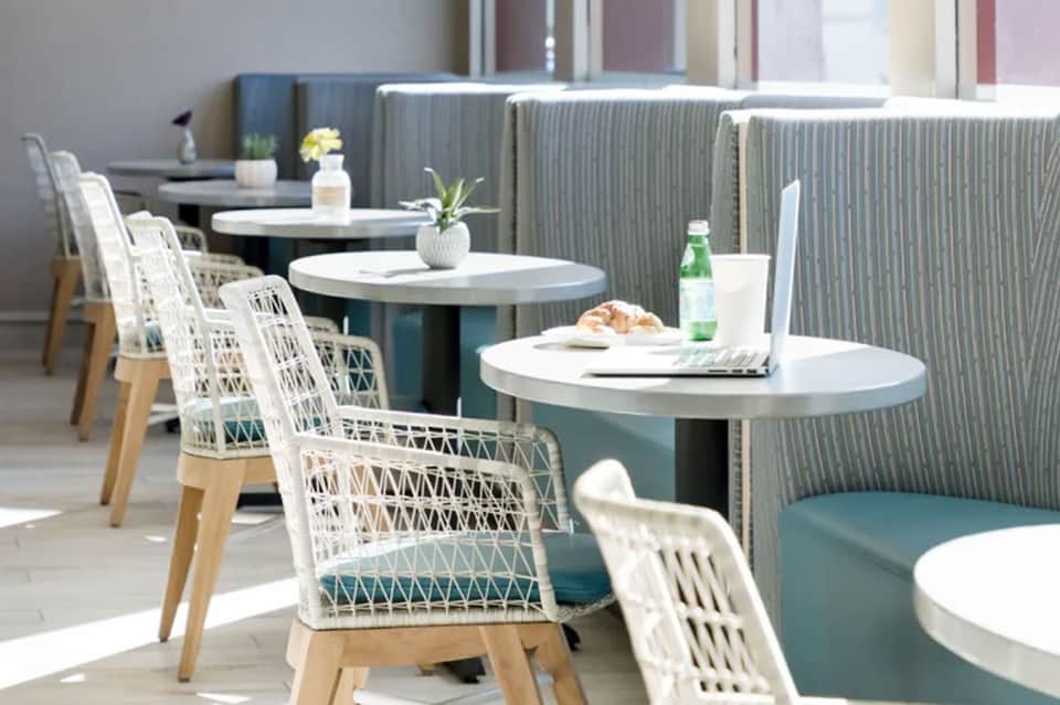 Modern indoor lounge with white woven chairs and teal booth seating