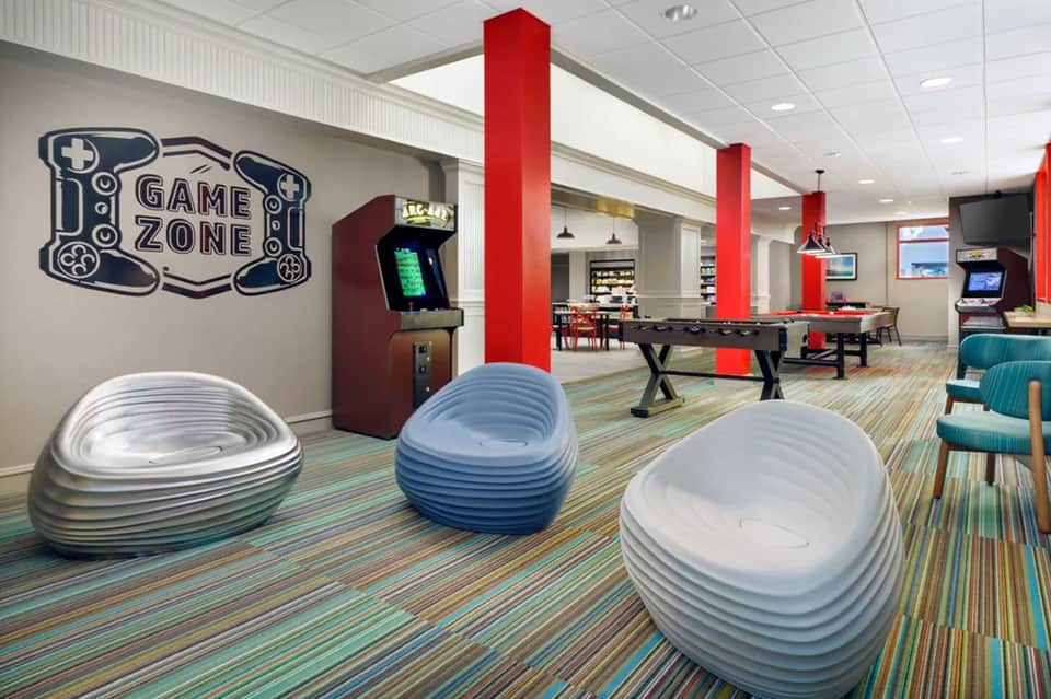 Game zone recreation room with arcade games, pool table, and colorful bean bag seating