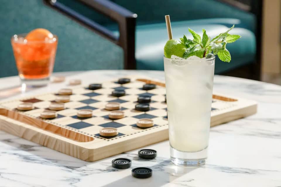 Outdoor bar seating with refreshing cocktails and checkers game on marble table