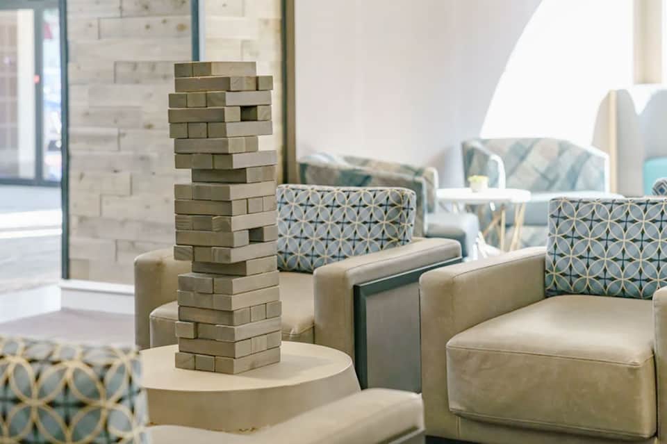 Modern hotel lounge with comfortable seating, geometric patterned pillows, and jenga game setup