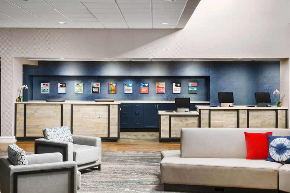 Contemporary hotel lobby with wooden reception desk, seating areas, and accent lighting