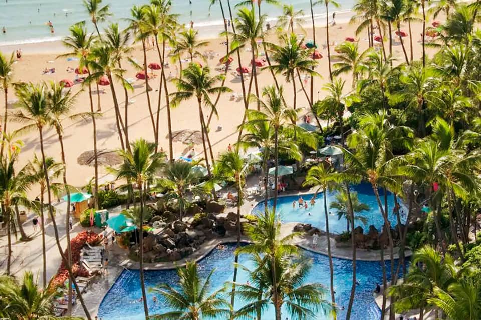 Aerial resort view with multiple pools, palm trees, and sandy beach access