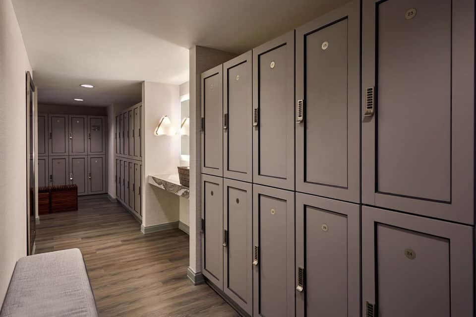Hotel locker room corridor with numbered gray storage lockers along wooden hallway