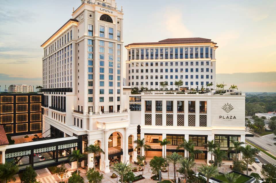 Elegant historic hotel plaza with white columns and palm trees at sunset