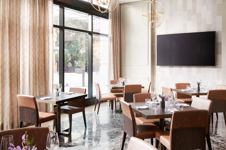 Modern hotel restaurant interior with brown leather chairs, tables, and large windows