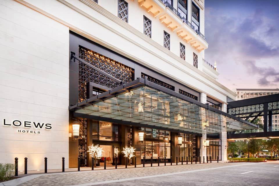 Luxury hotel entrance with glass canopy, ornate metalwork, and elegant white stone facade at dusk