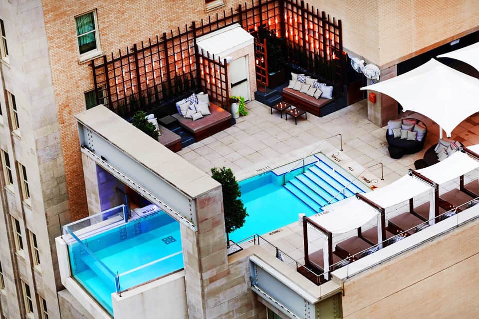 Rooftop pool area with lap pool, loungers, and brick building architecture