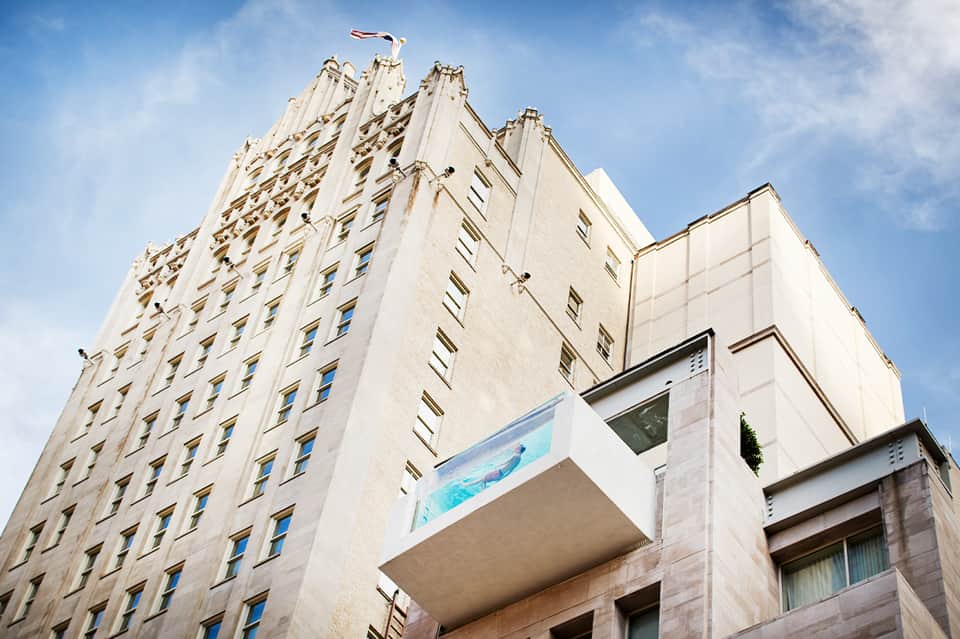 Historic cream-colored hotel building exterior with ornate architectural details and flag on roof