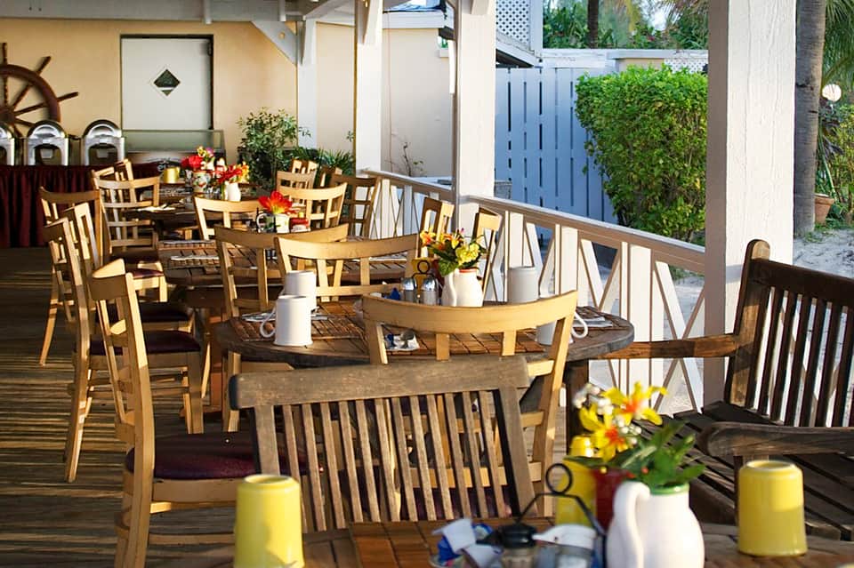 Outdoor dining area with wooden tables, chairs, and decorative floral arrangements
