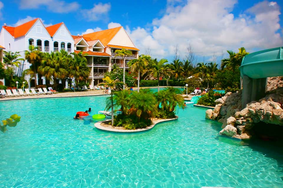 Turquoise lagoon with orange-roofed mansion, palm trees, and waterslide