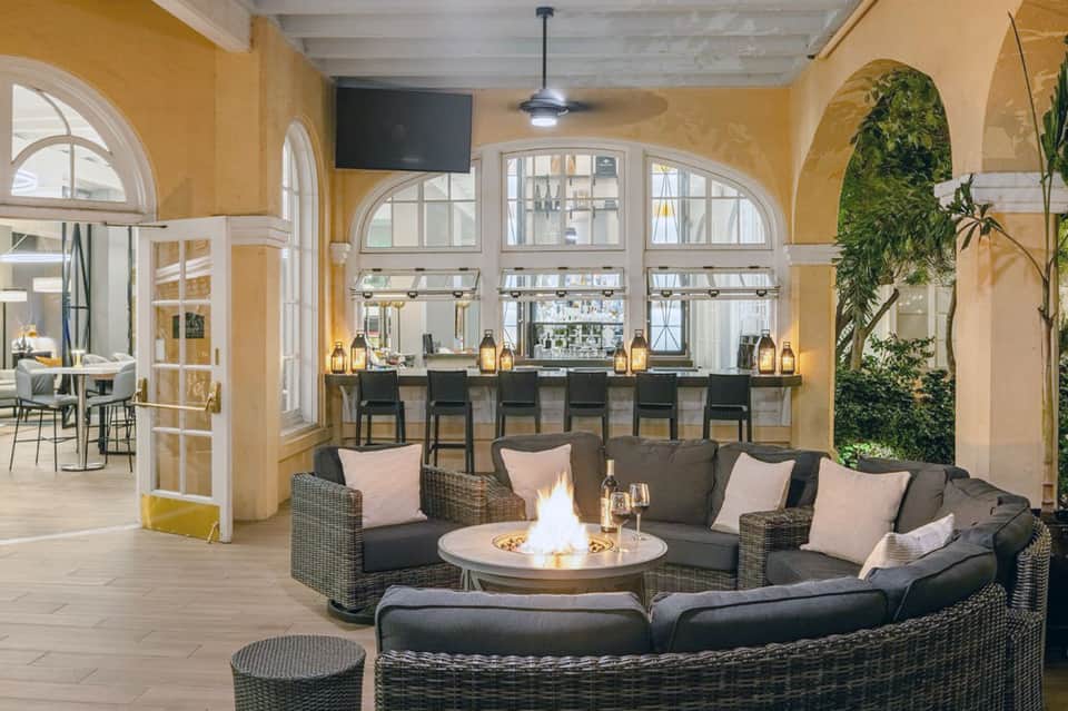 Elegant lounge with bar, fireplace, hanging plants, and arched windows