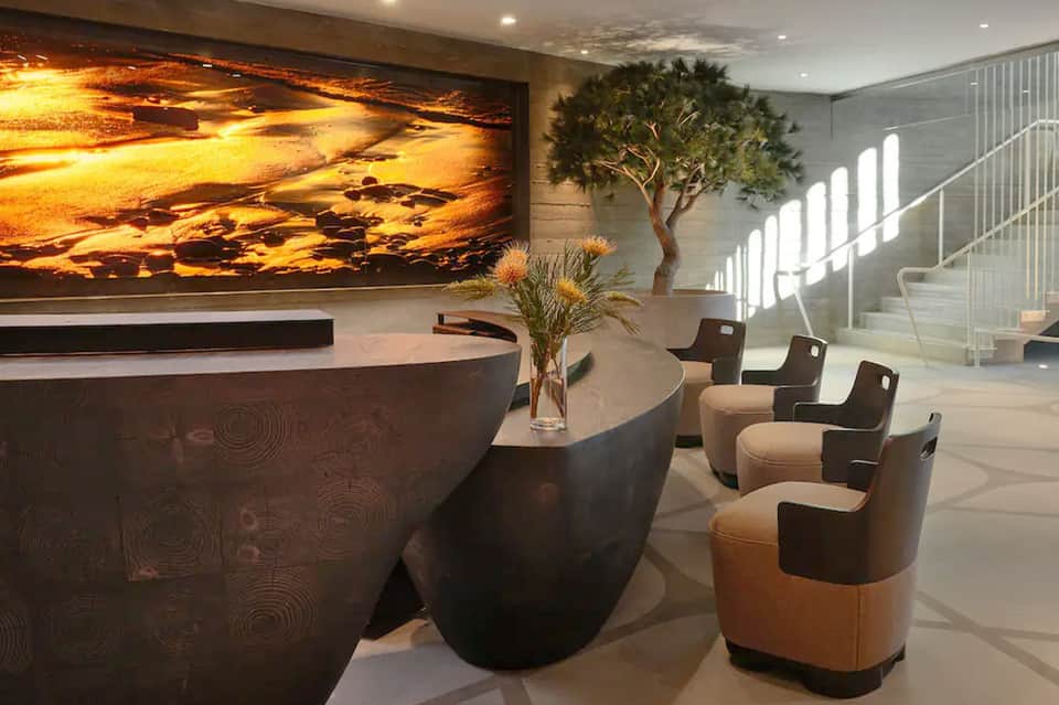 Modern hotel lobby with curved reception desk, dramatic sunset artwork, and seating area