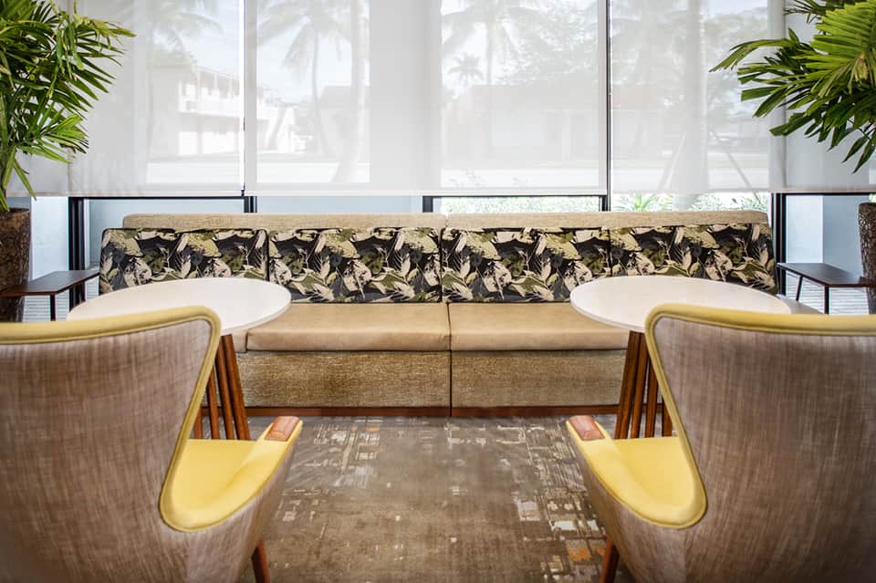Modern lobby lounge with patterned sofa and mid-century chairs by windows