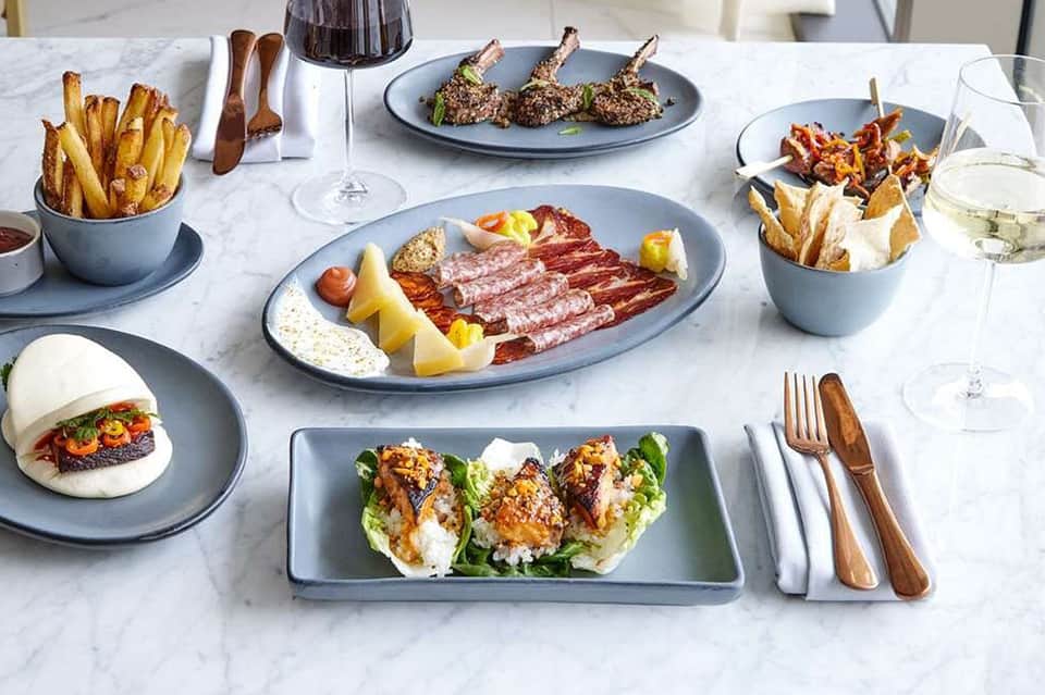 Fine dining table with gourmet appetizers, charcuterie, fries, wine, and refined plating