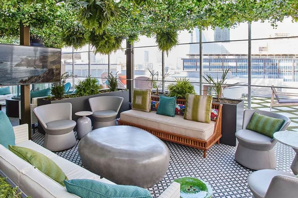 Rooftop lounge area with modern seating, hanging plants, and urban cityscape views