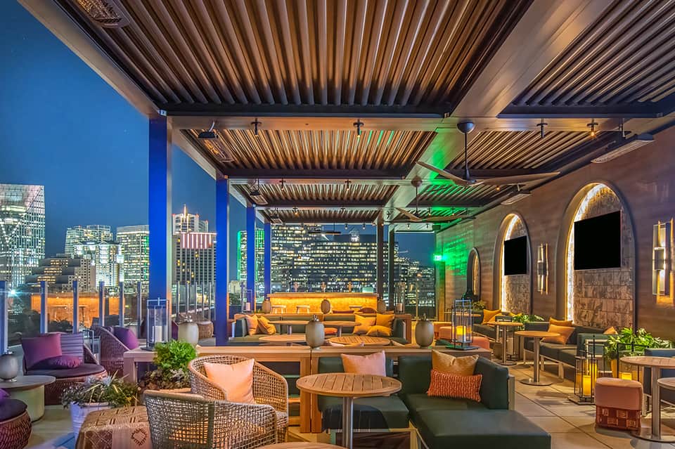 Upscale rooftop lounge with city skyline, modern seating, and ambient lighting