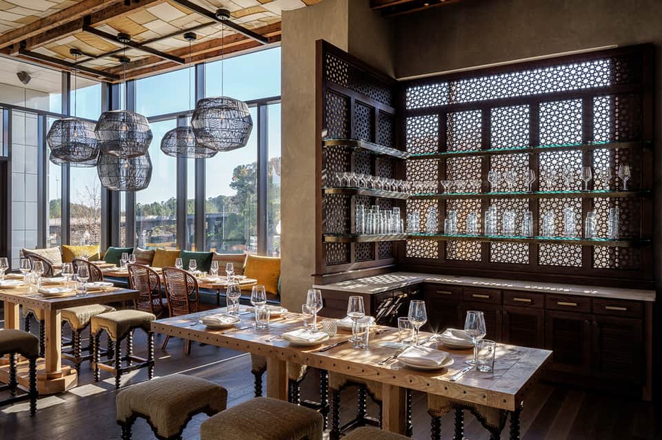 Upscale restaurant with wooden beamed ceiling, pendant lights, and geometric shelf display