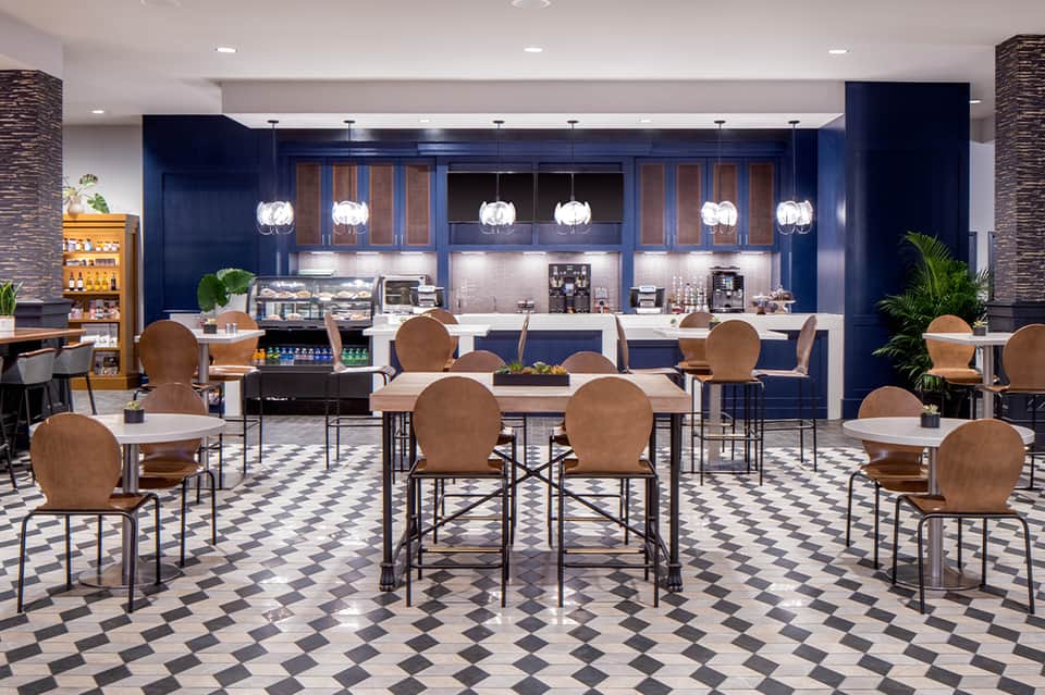 Modern hotel cafe with navy cabinetry, pendant lighting, and dining seating in contemporary design
