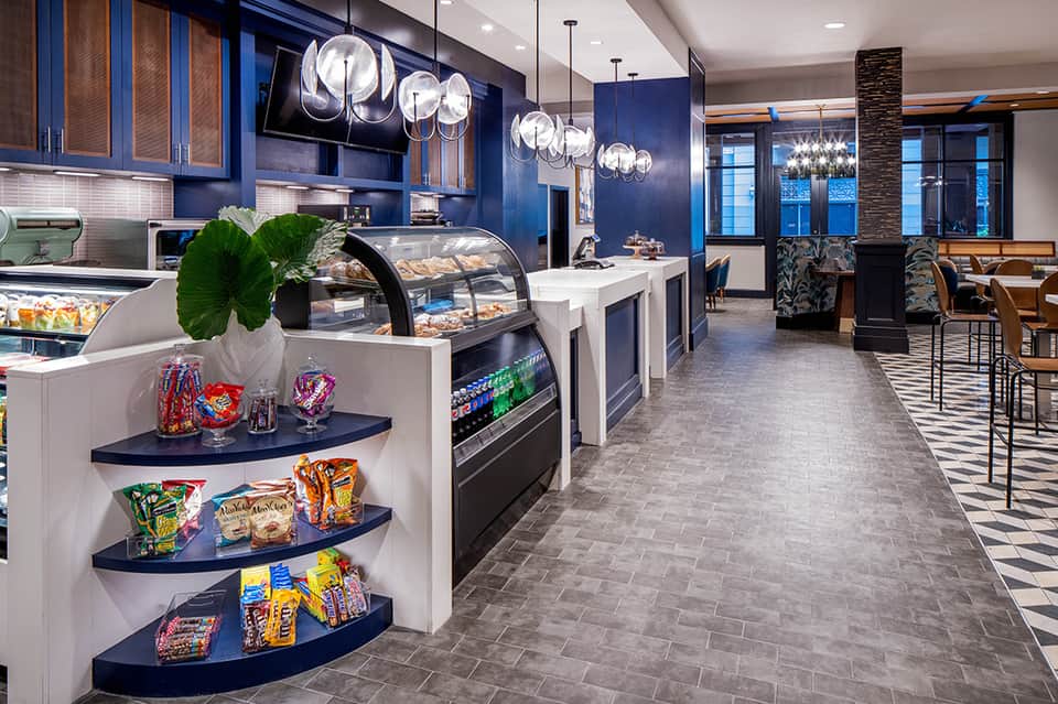 Modern hotel café interior with blue cabinetry, bakery display, and pendant lighting