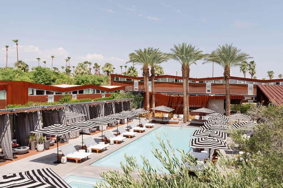 Contemporary pool area with striped umbrellas, lounge chairs, and palm trees