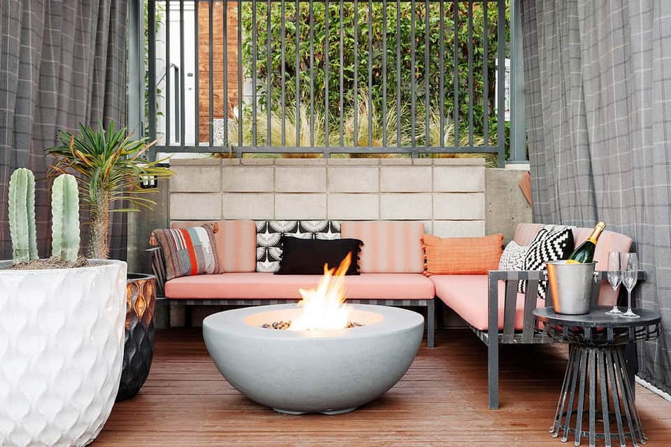Modern patio with pink sofa, fire pit, plants, and city views