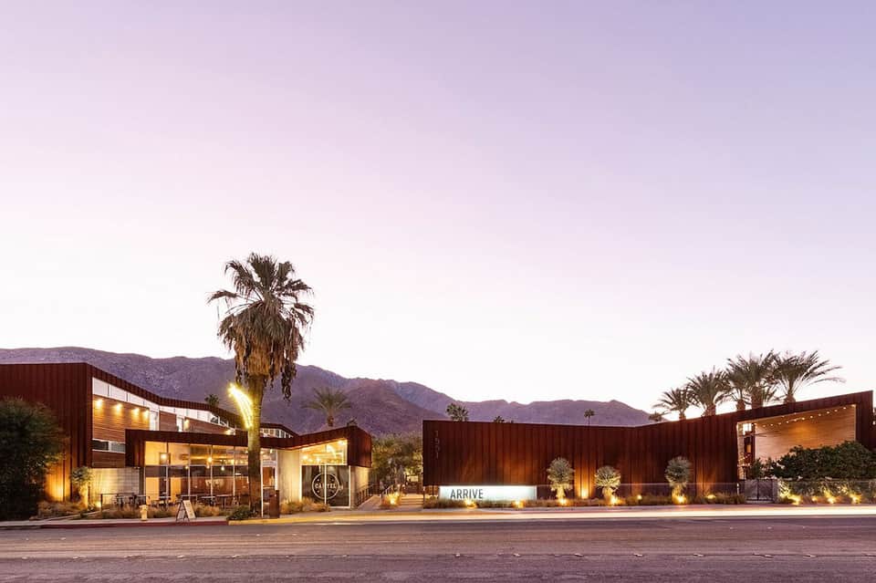 Modern desert resort entrance at dusk with warm lighting and palm trees