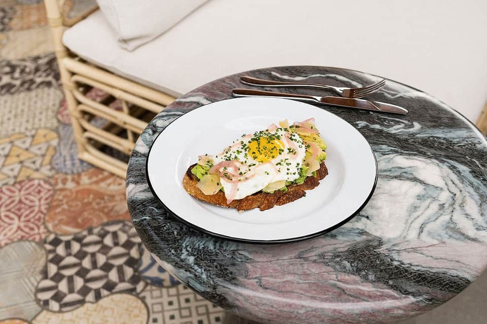 Artfully plated egg and avocado toast on marble table setting