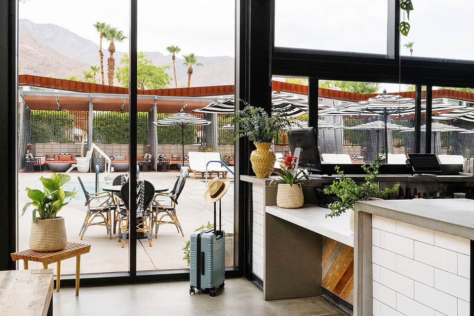 Resort lobby and lounge area with large windows overlooking palm trees and mountains