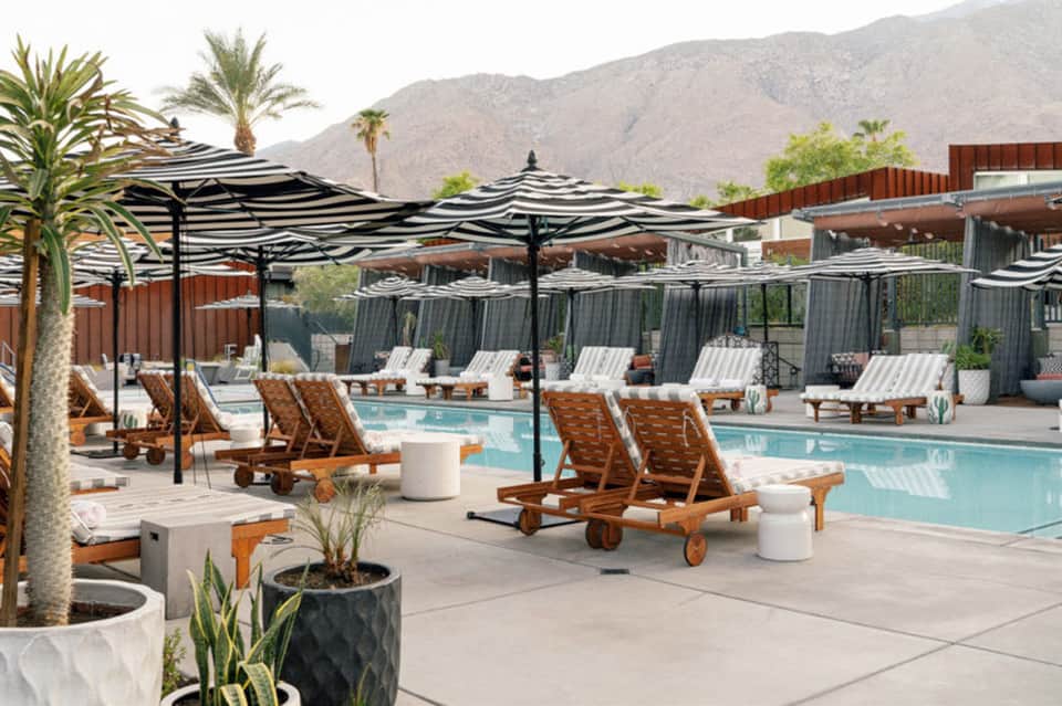 Luxury resort pool with striped umbrellas, loungers, and desert mountain backdrop