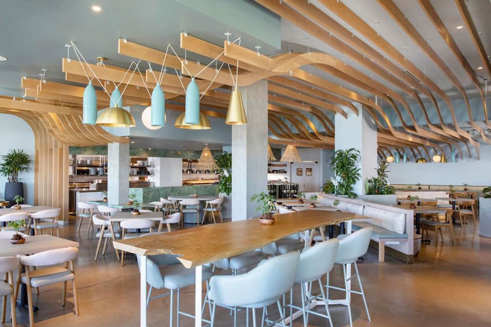 Modern dining space with wooden beam ceiling, contemporary pendant lights, and white seating