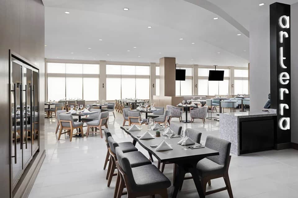 Contemporary restaurant dining room with floor-to-ceiling windows and modern place settings