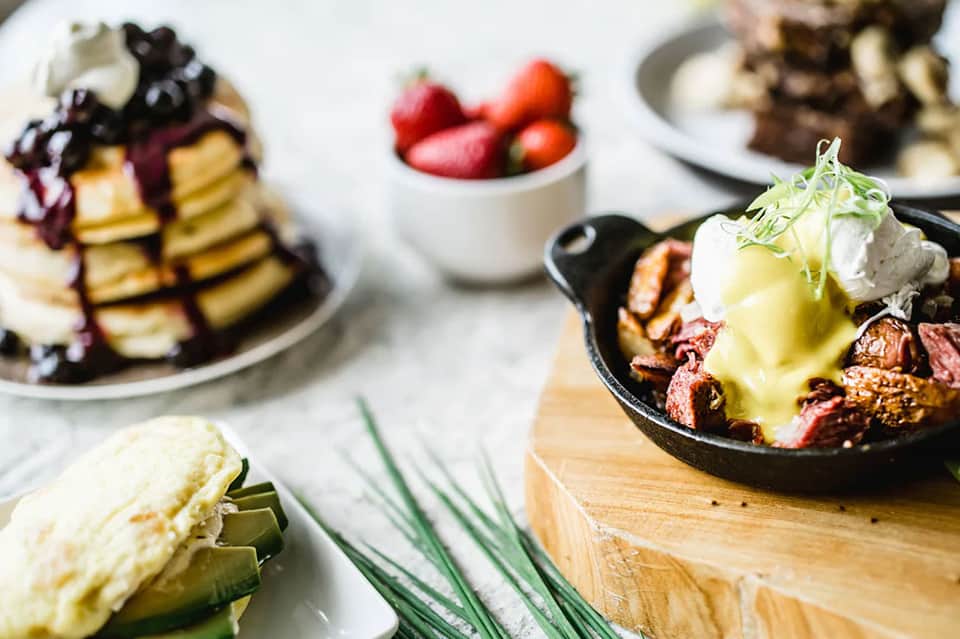 Gourmet brunch spread with pancakes, eggs, fruit, and specialty dishes on table