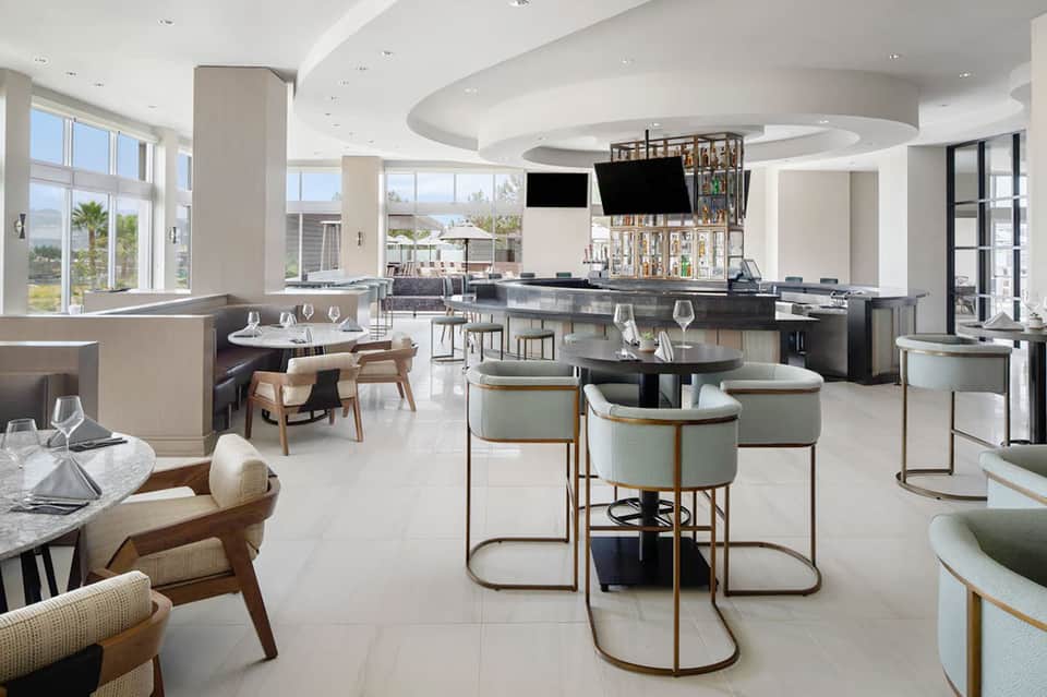 Modern upscale restaurant and bar interior with curved ceiling, contemporary furniture, and ocean views