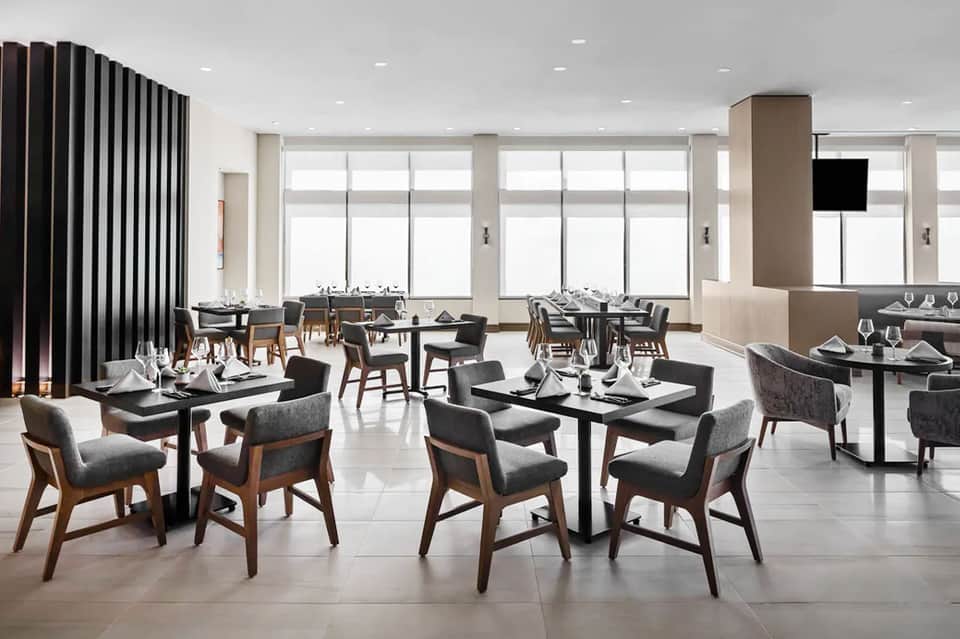 Upscale dining room with black tables, modern chairs, floor-to-ceiling windows, contemporary design