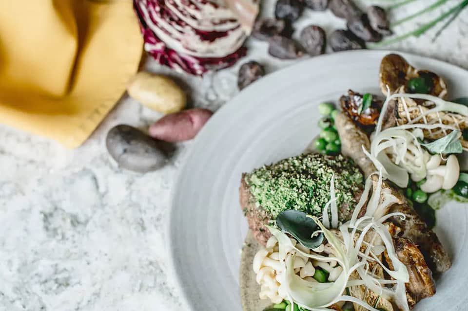 Elegant plated seafood dish with green garnish and fresh vegetables on white plate