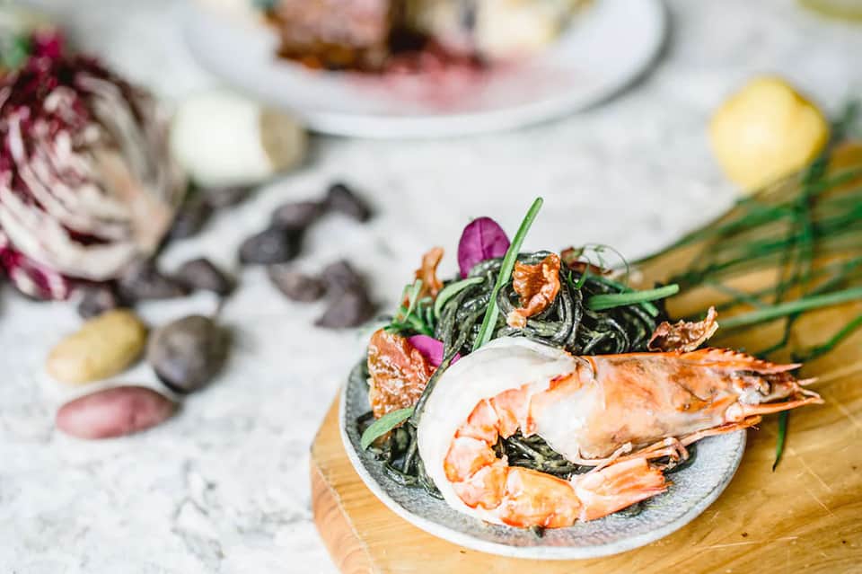 Gourmet plated seafood dish with garnish and fresh ingredients on white tablecloth