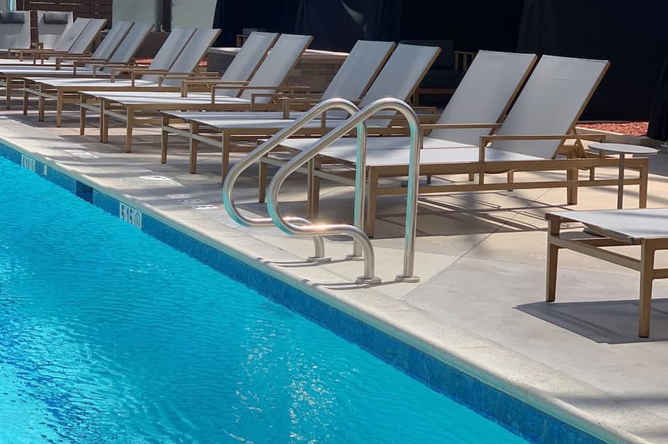 Poolside lounge chairs with metal handrails next to crystal-clear turquoise swimming pool