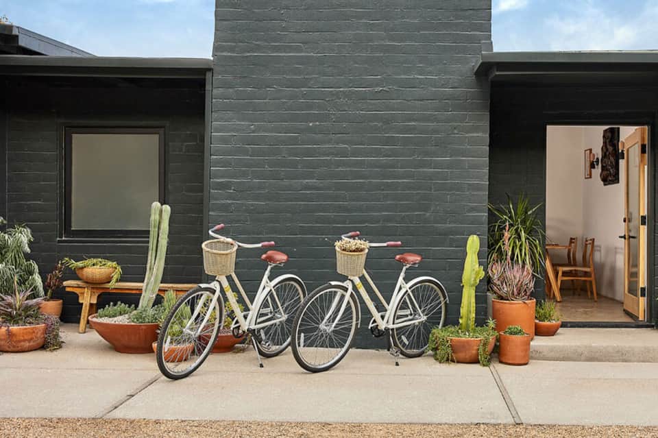 Modern black home exterior with bicycles parked outside and potted cacti decoration