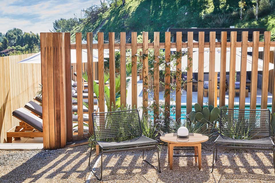 Wooden pergola lounge area with seating overlooking pool and landscaped hillside garden