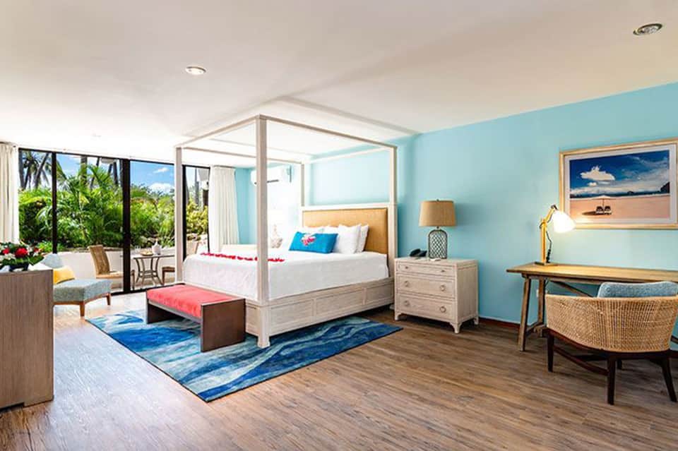 Tropical resort bedroom with turquoise walls, four-poster bed, ocean view, and contemporary furnishings
