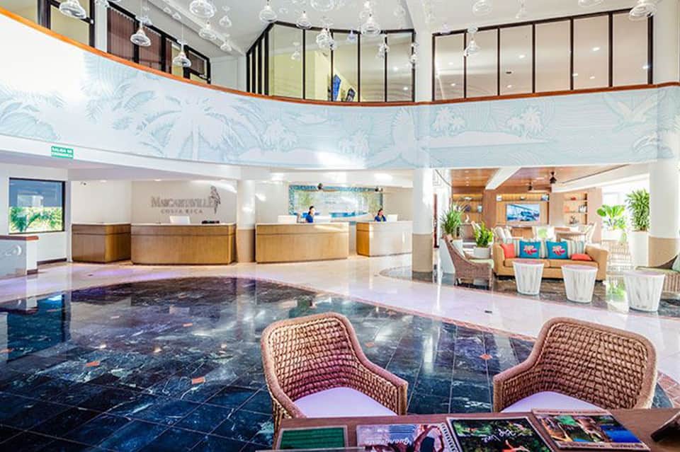 Hotel lobby with curved reception desk, tropical mural, and seating lounge area