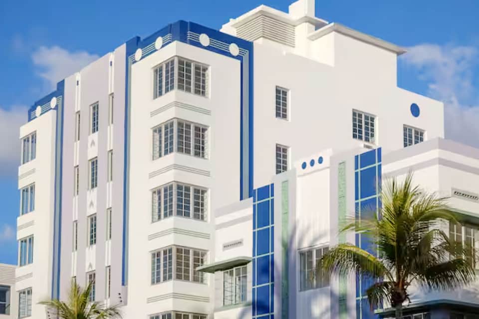 Art deco style hotel building facade in white and blue with palm trees