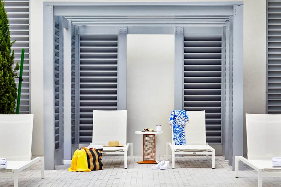 Modern poolside cabana with white lounge chairs and dark shuttered doors