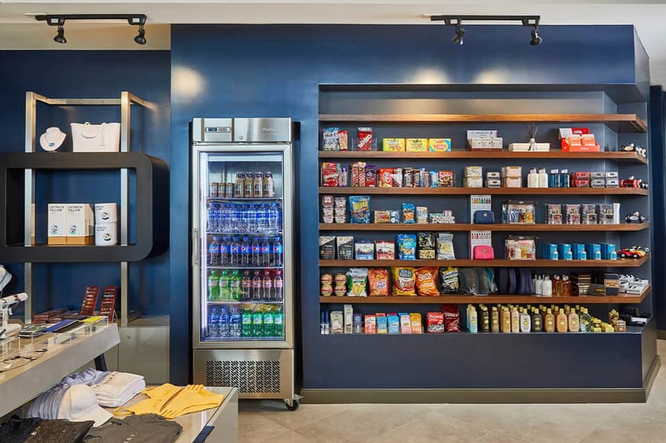 Modern convenience store interior with blue walls, beverage cooler, and extensive snack shelving