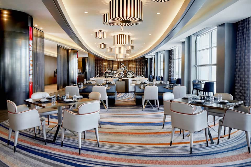 Upscale dining room with curved ceiling, decorative pendant lights, striped carpet, and formal table settings