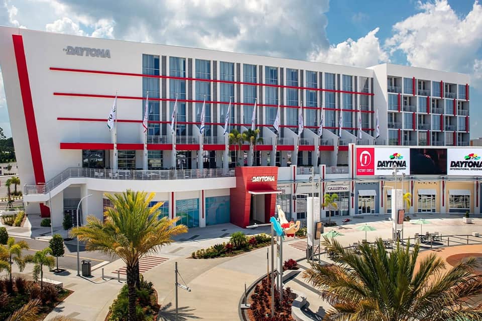 Modern Daytona hotel building with red and white striped facade and palm tree landscaping